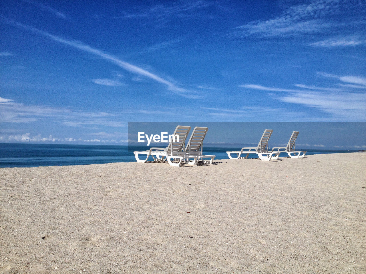 Lounge chairs on sea shore against sky