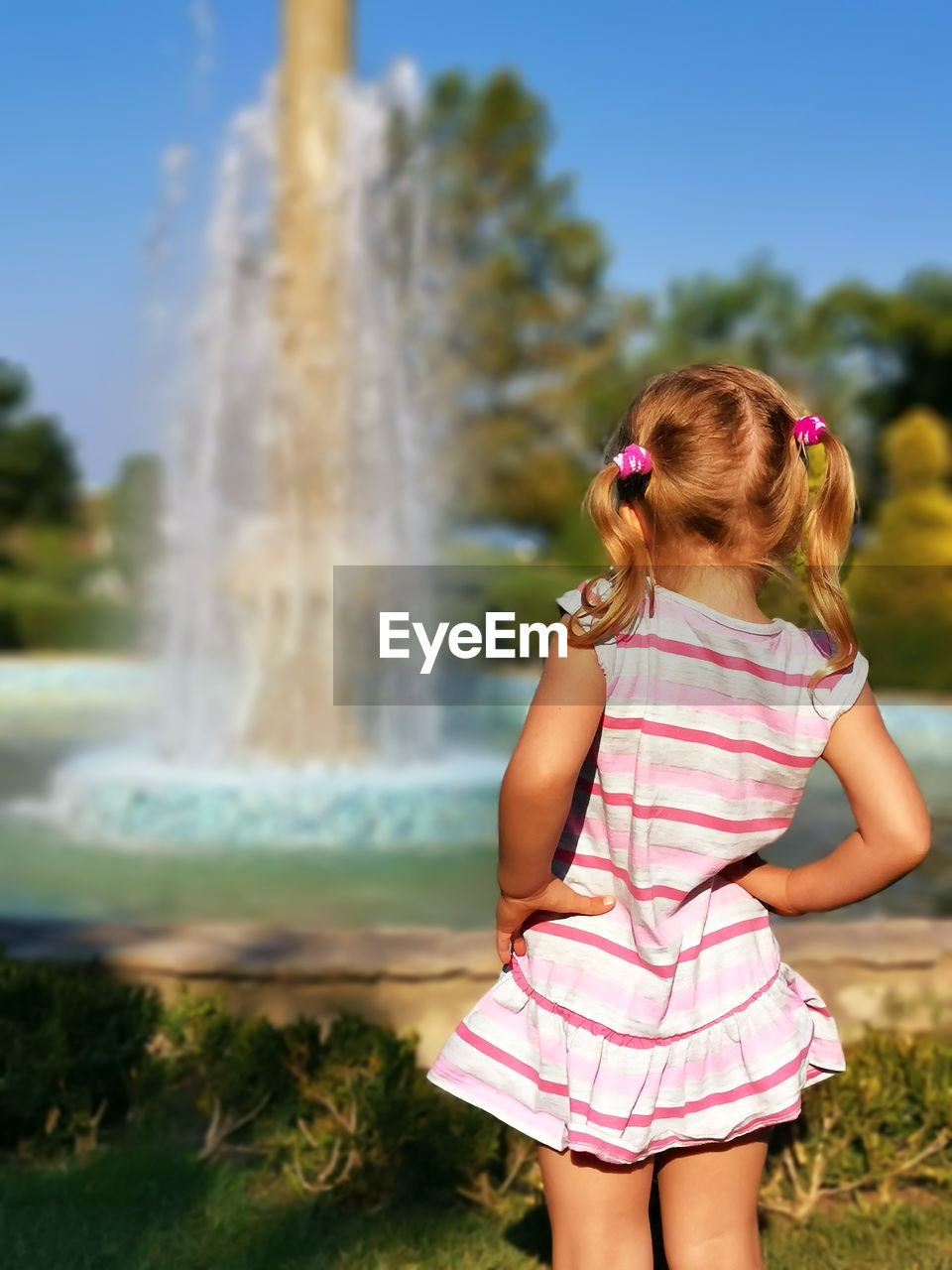 Rear view of girl looking at fountain in park