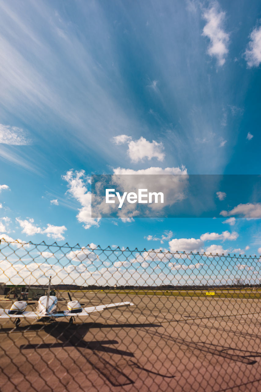 Airplane at runway against cloudy sky