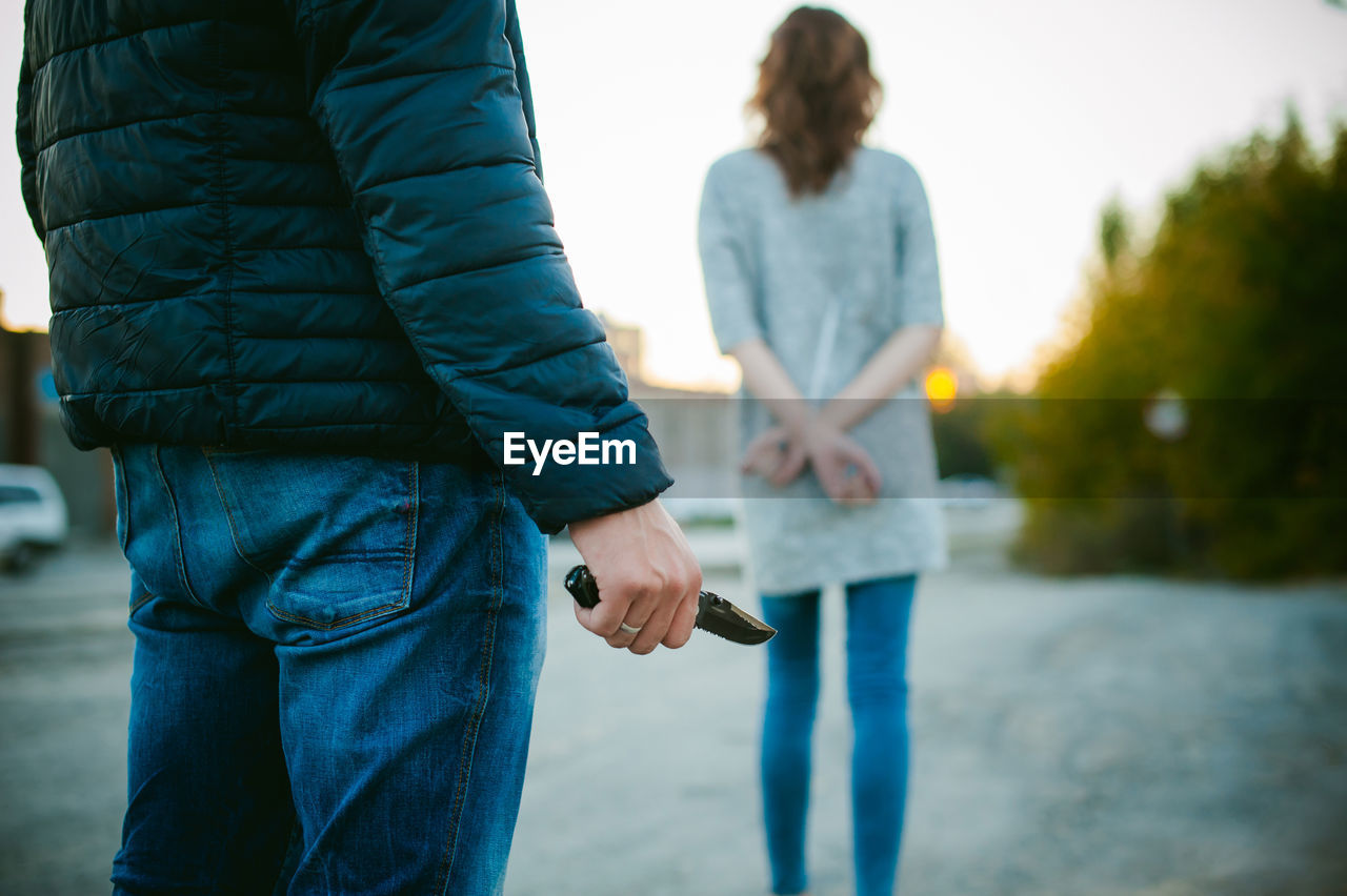 Rear view of man standing with knife against woman