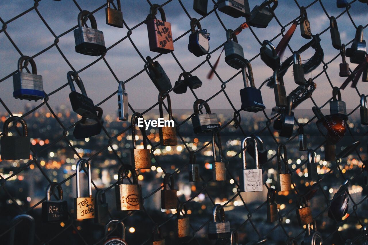 CLOSE-UP OF PADLOCKS HANGING IN CHAINLINK FENCE