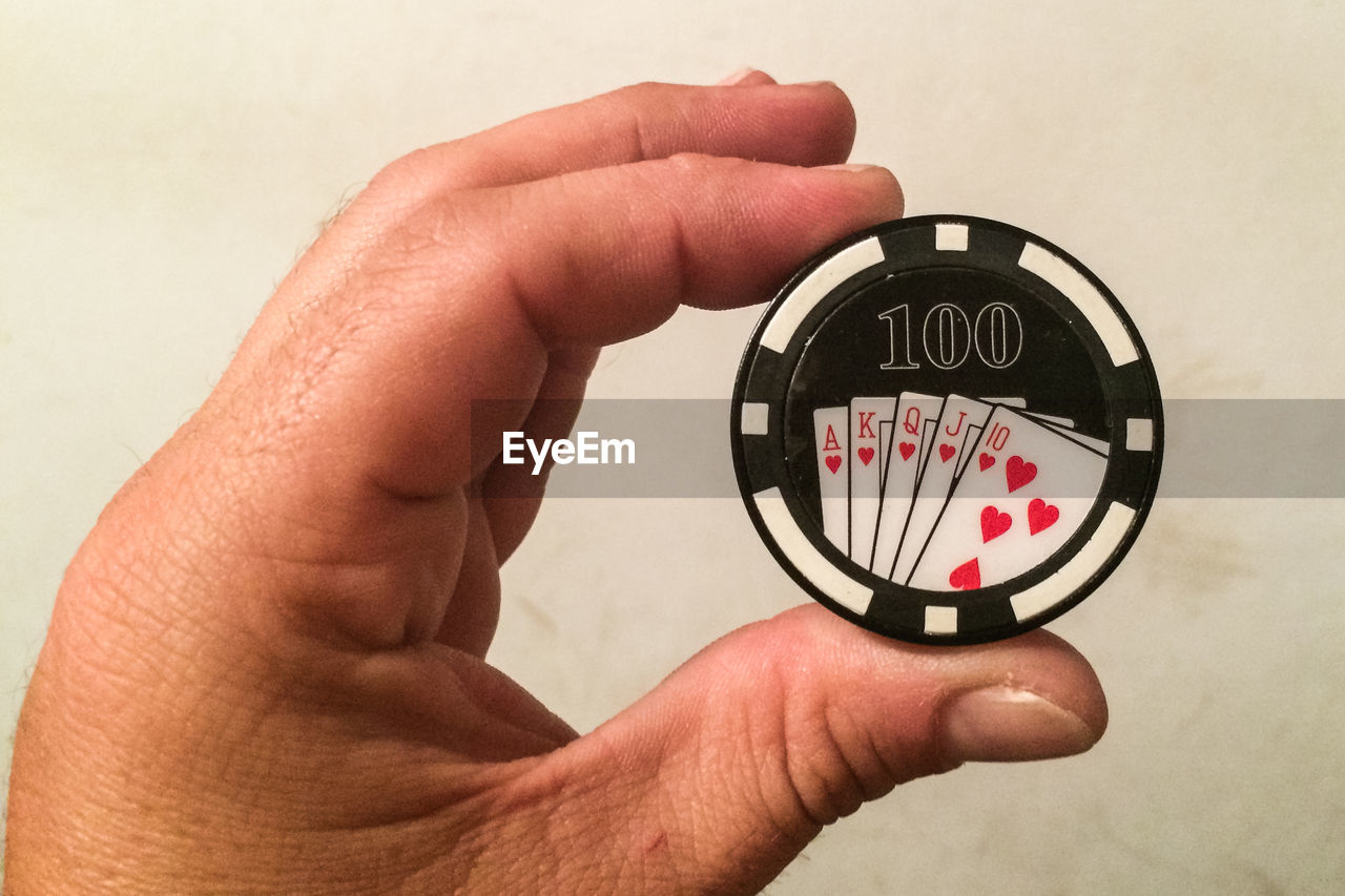 CLOSE-UP OF HUMAN HAND HOLDING CLOCK