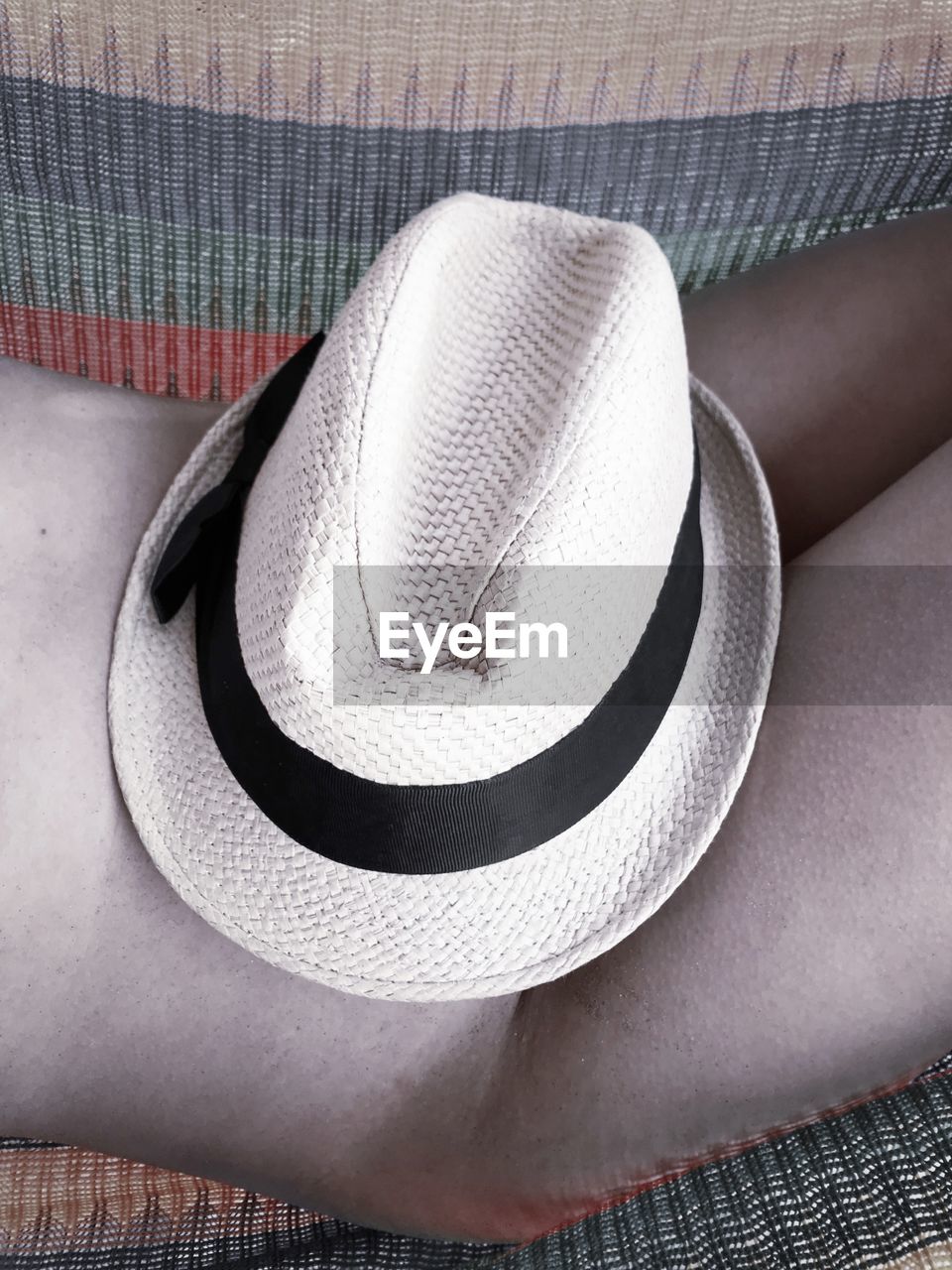 Midsection of woman with hat relaxing on hammock