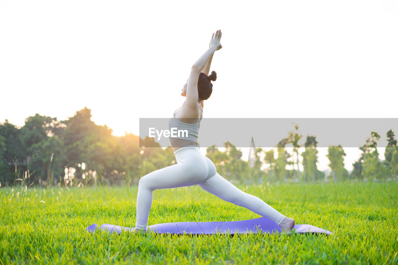 full length of woman doing yoga on field against clear sky