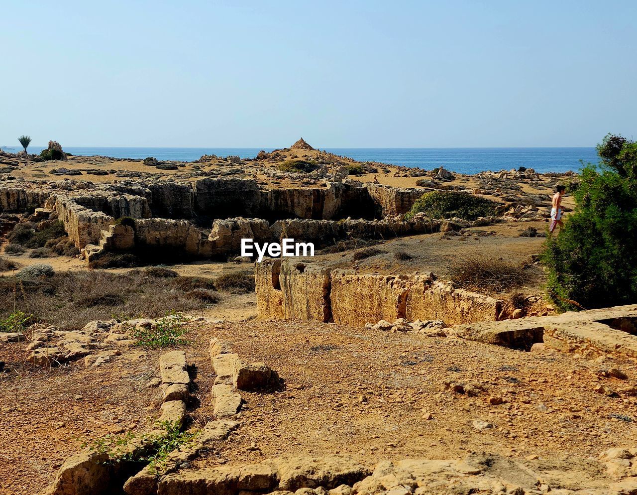 sky, rock, land, nature, landscape, sea, scenics - nature, water, ruins, clear sky, geology, tranquility, ancient history, day, travel destinations, no people, natural environment, beauty in nature, tranquil scene, terrain, cliff, coast, beach, travel, history, rock formation, non-urban scene, wadi, sunlight, outdoors, environment, horizon, architecture, tourism, the past, horizon over water, ancient, sunny, plant, blue