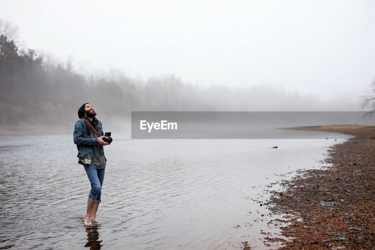 Full length of man in lake against sky during winter