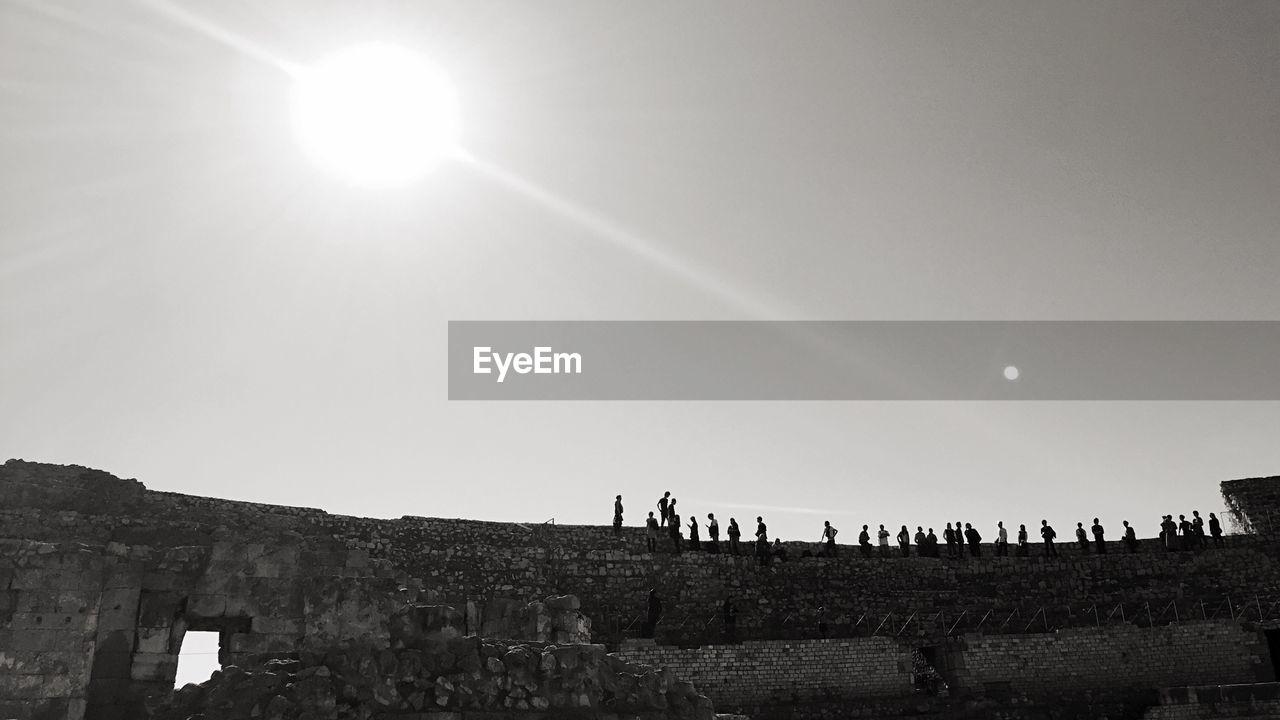 Low angle view of people at tarragona amphitheatre against sky in city