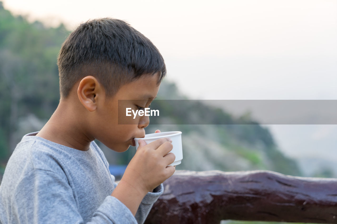 Boy drinking coffee at remote location