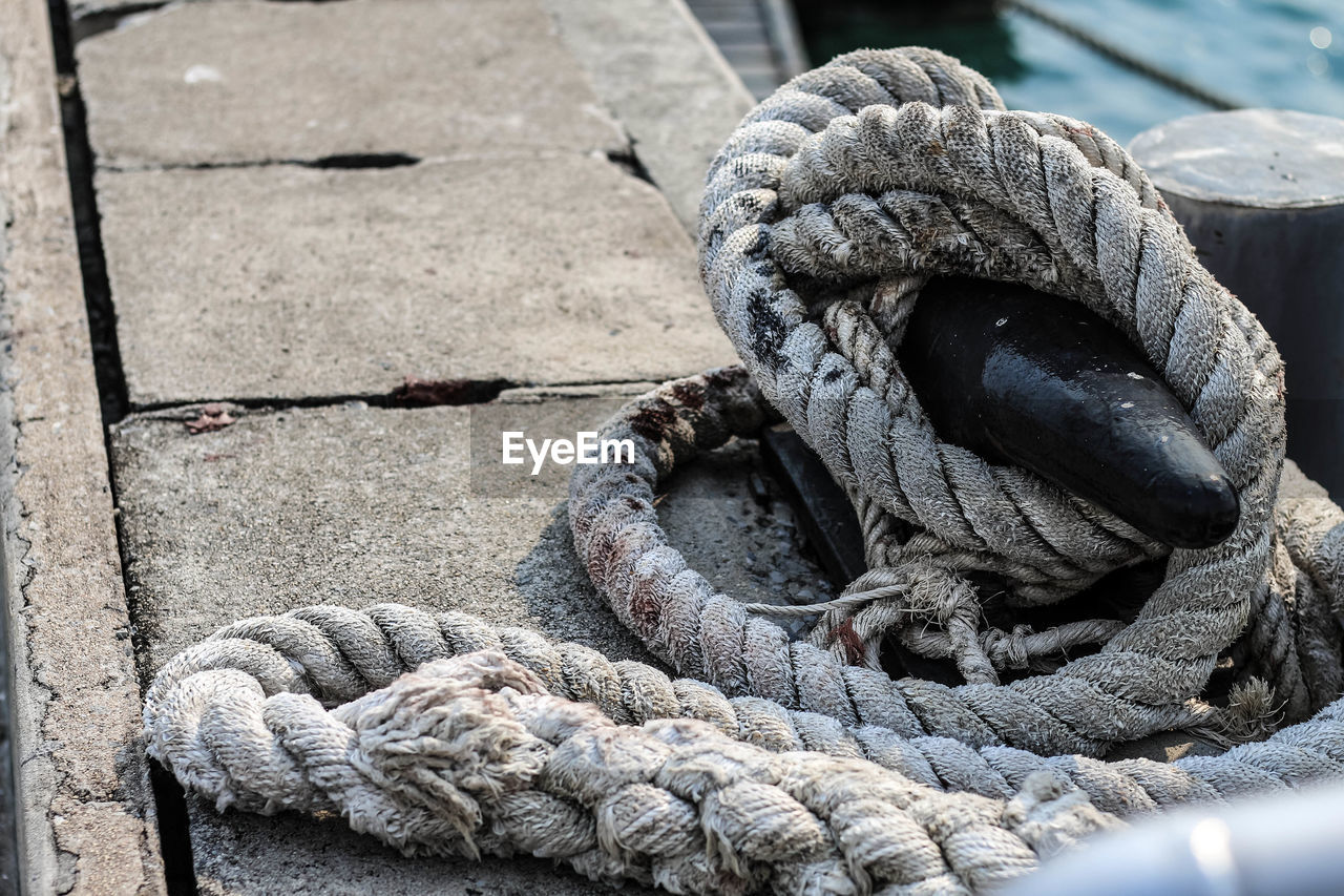 Close-up of rope tied on bollard at harbor