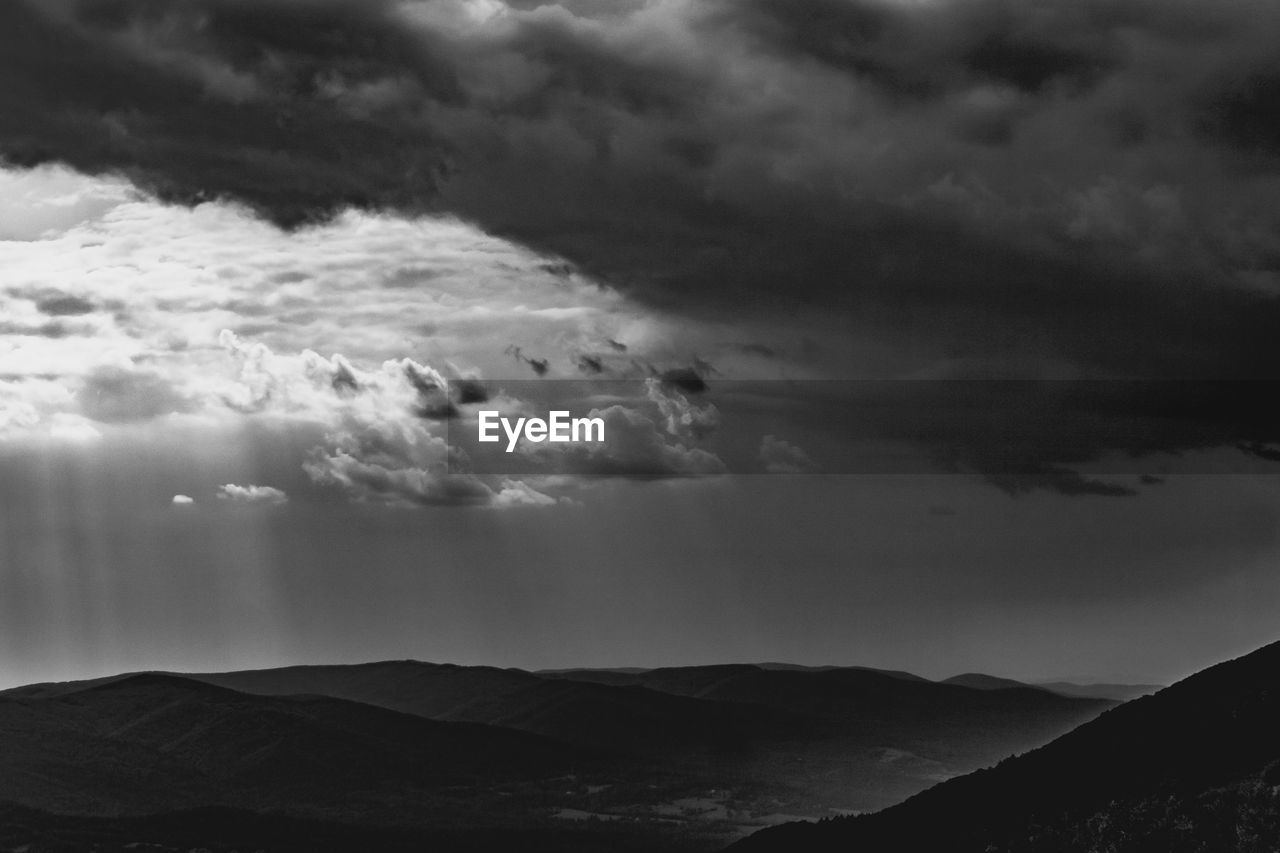 SCENIC VIEW OF MOUNTAINS AGAINST STORM CLOUDS