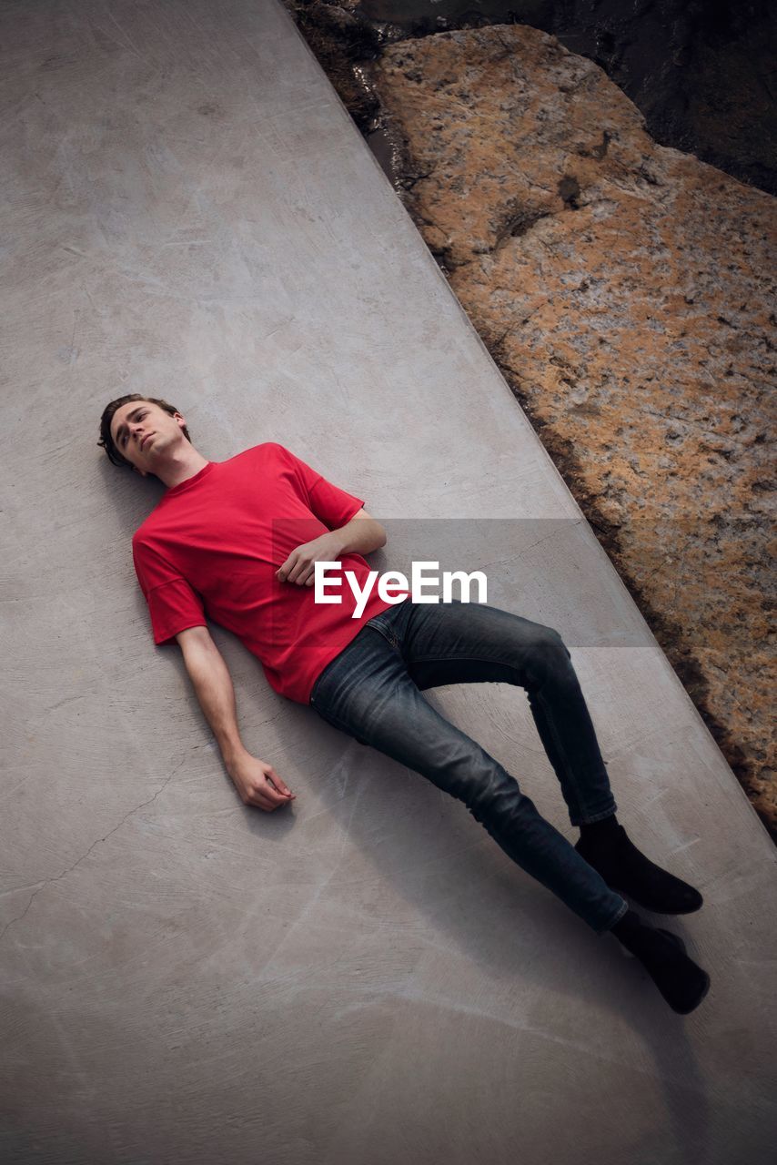 HIGH ANGLE VIEW OF YOUNG MAN LYING DOWN