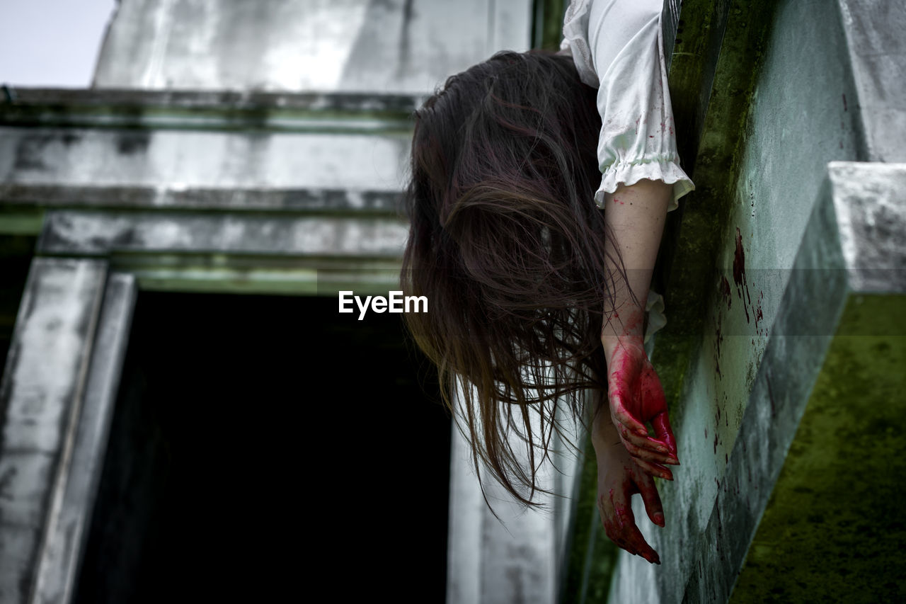 Low angle view of woman hanging on building wall during halloween