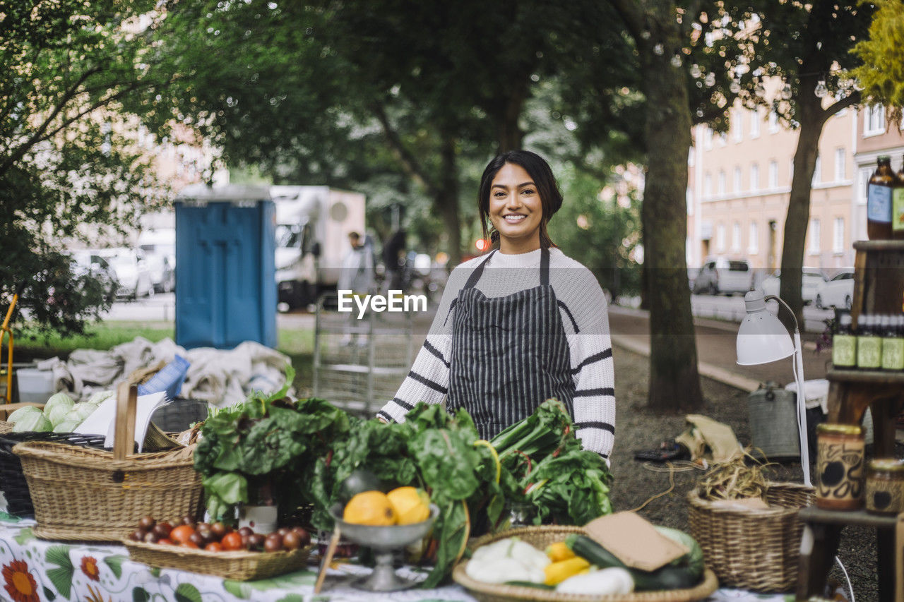 Portrait of smiling female vendor selling vegetables at farmer's market