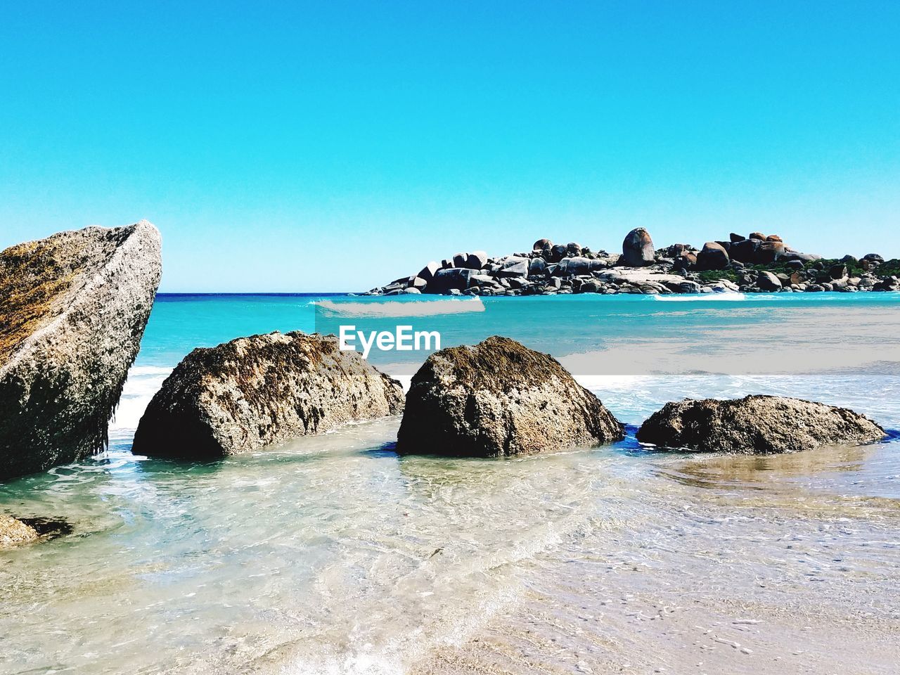 PANORAMIC VIEW OF ROCKS ON BEACH AGAINST CLEAR BLUE SKY