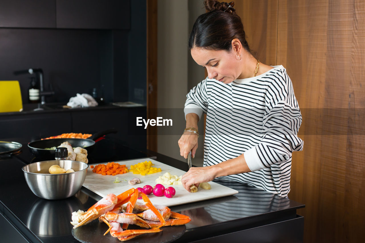 Woman slicing vegetables while cooking stew. close up of woman hands cutting vegetables