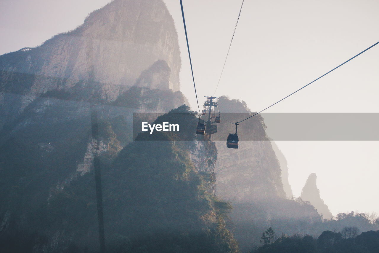 Low angle view of overhead cable cars against mountains