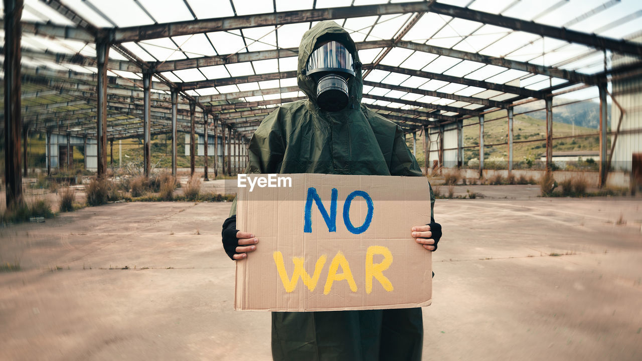 Boy with gas mask holds in hand cardboard with no war text