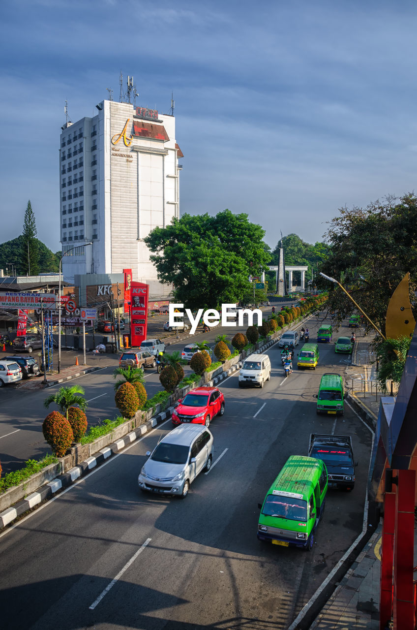 CARS ON ROAD BY BUILDINGS AGAINST SKY