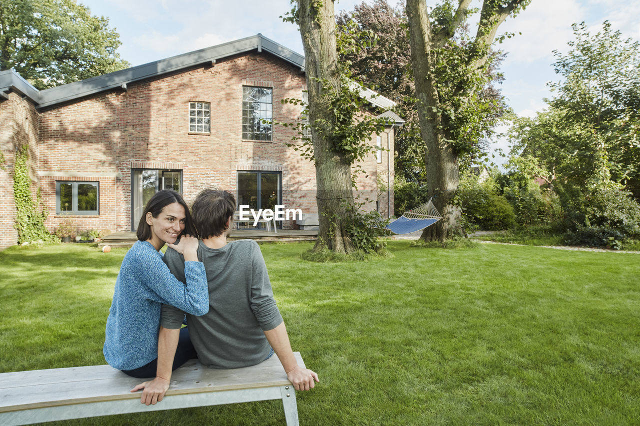 Smiling affectionate couple sitting in garden of their home