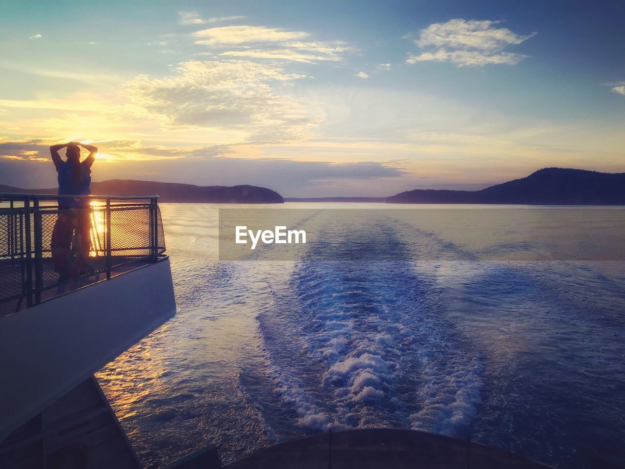 Man on boat in sea against sky during sunset