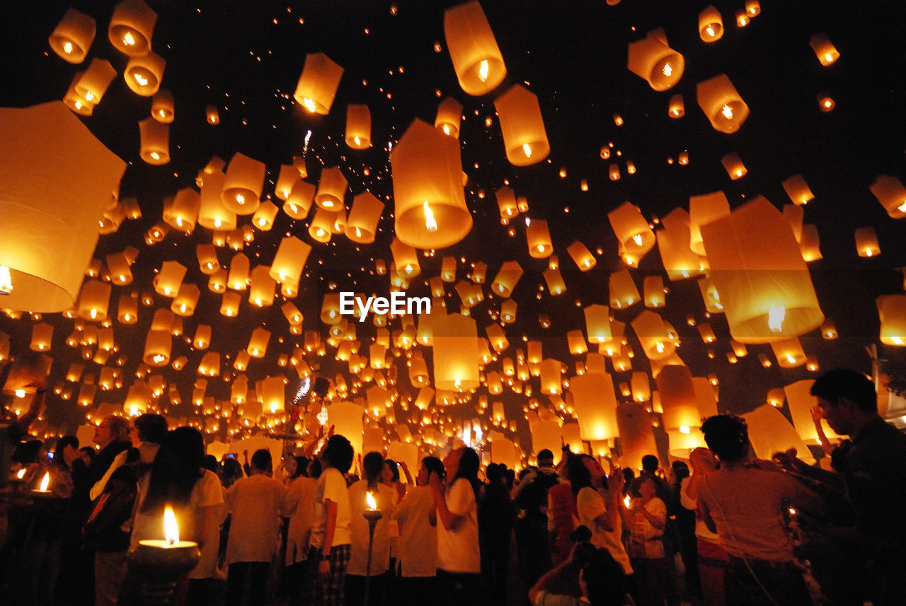 Crowd standing against lit paper lanterns at night