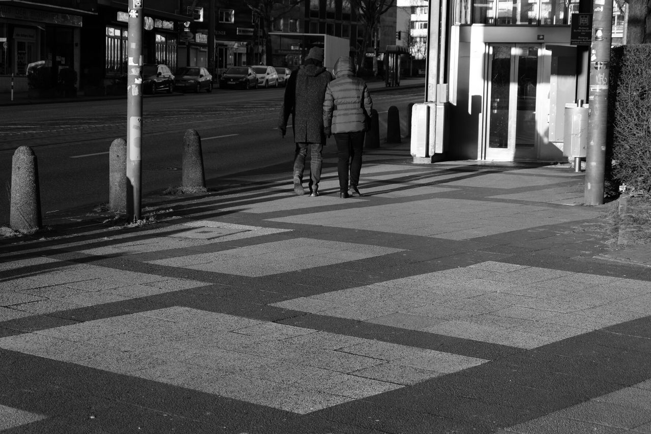 REAR VIEW OF PEOPLE WALKING ON ROAD