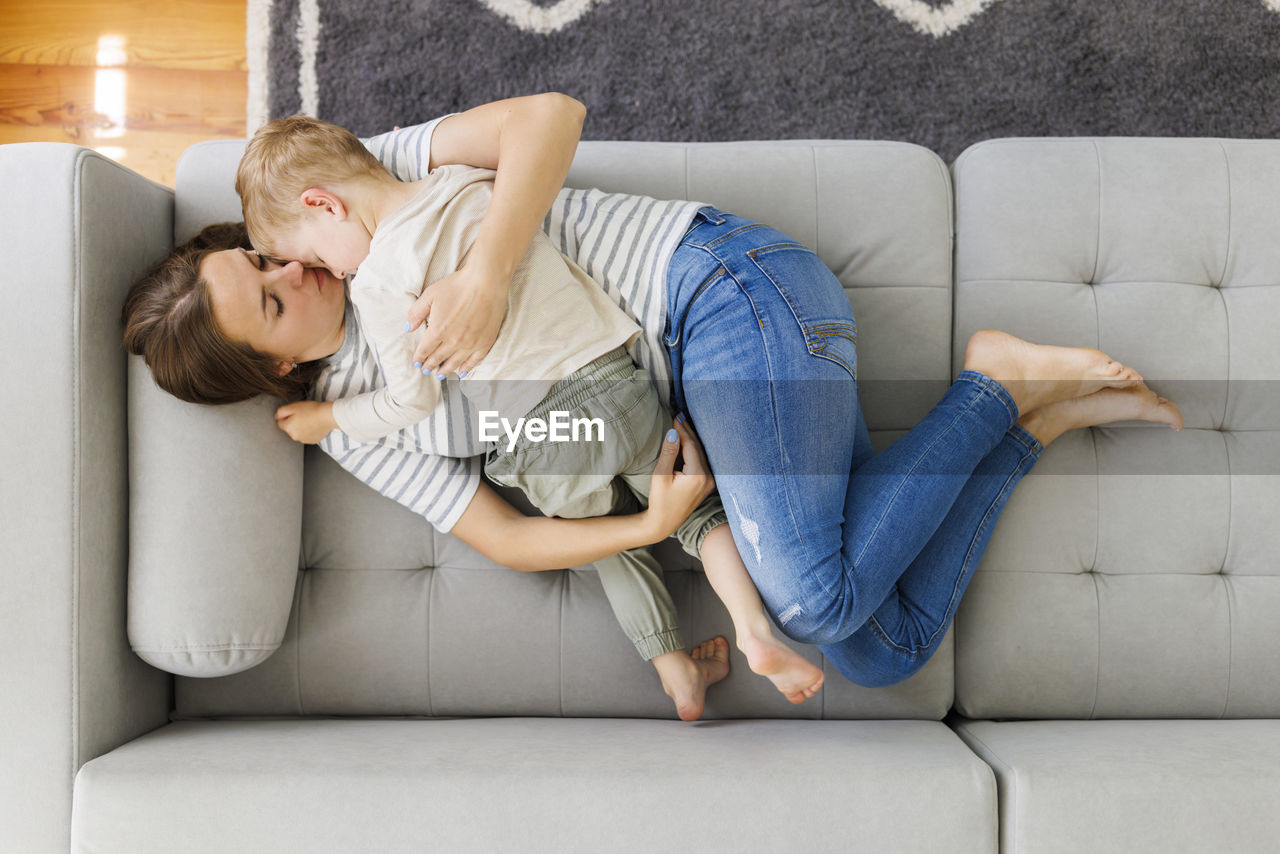 portrait of mother and daughter using digital tablet while sitting on sofa at home