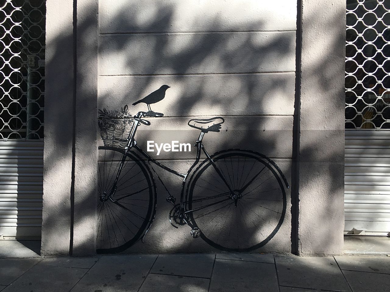 SHADOW OF BICYCLE ON METAL FENCE BY TILED FLOOR