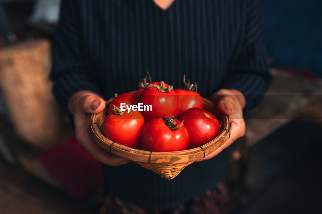 Man holding red chili peppers in basket