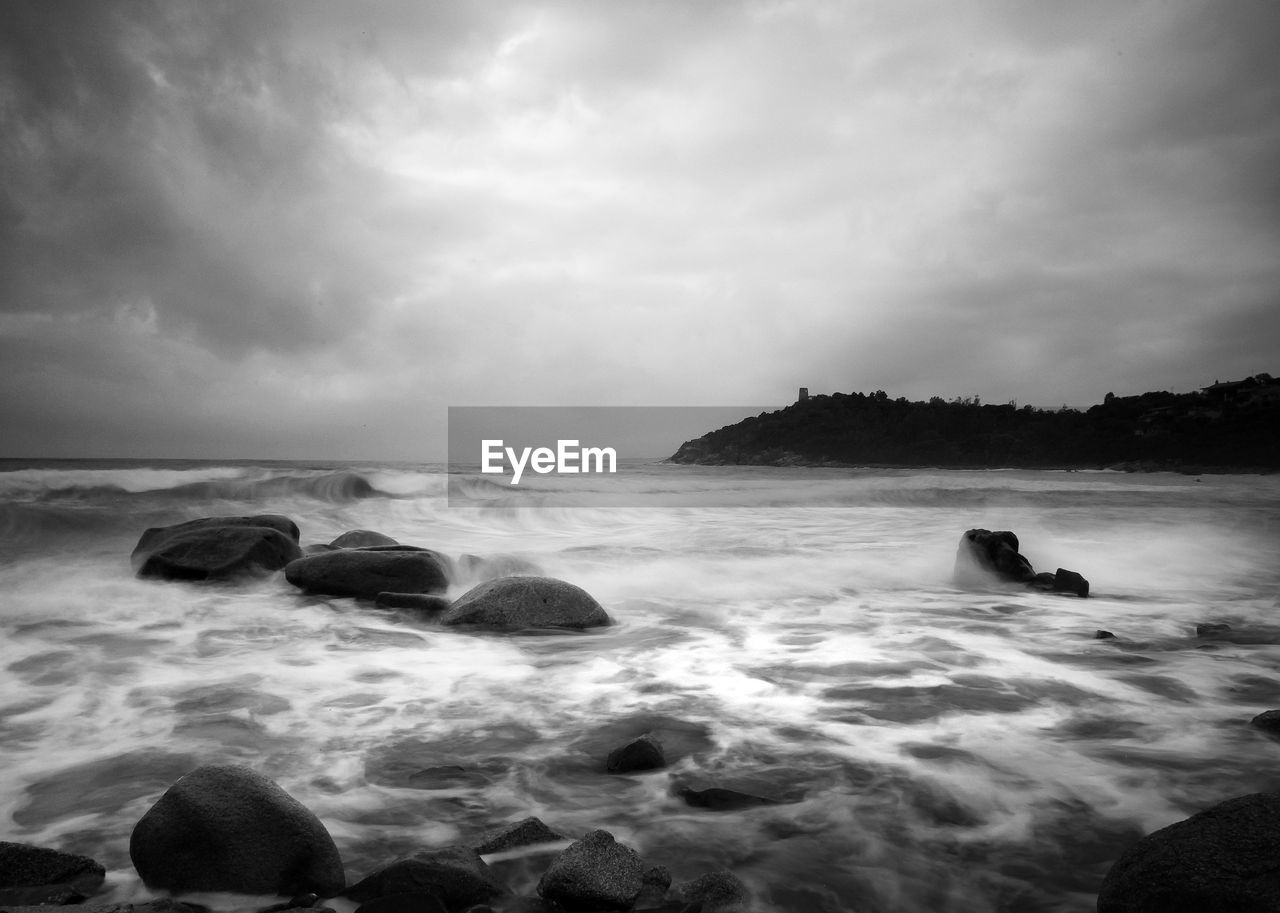 ROCKS ON SHORE AGAINST SKY