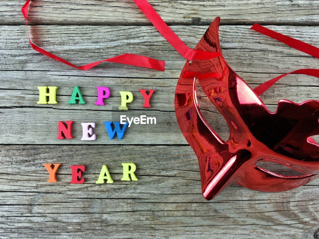 High angle view of mask with happy new year text on wooden table