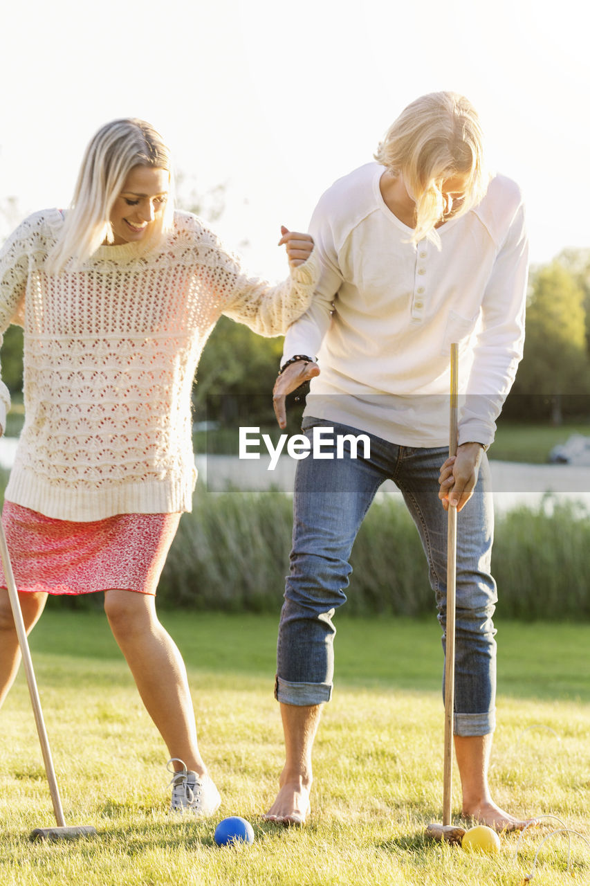 Happy friends playing croquet on field