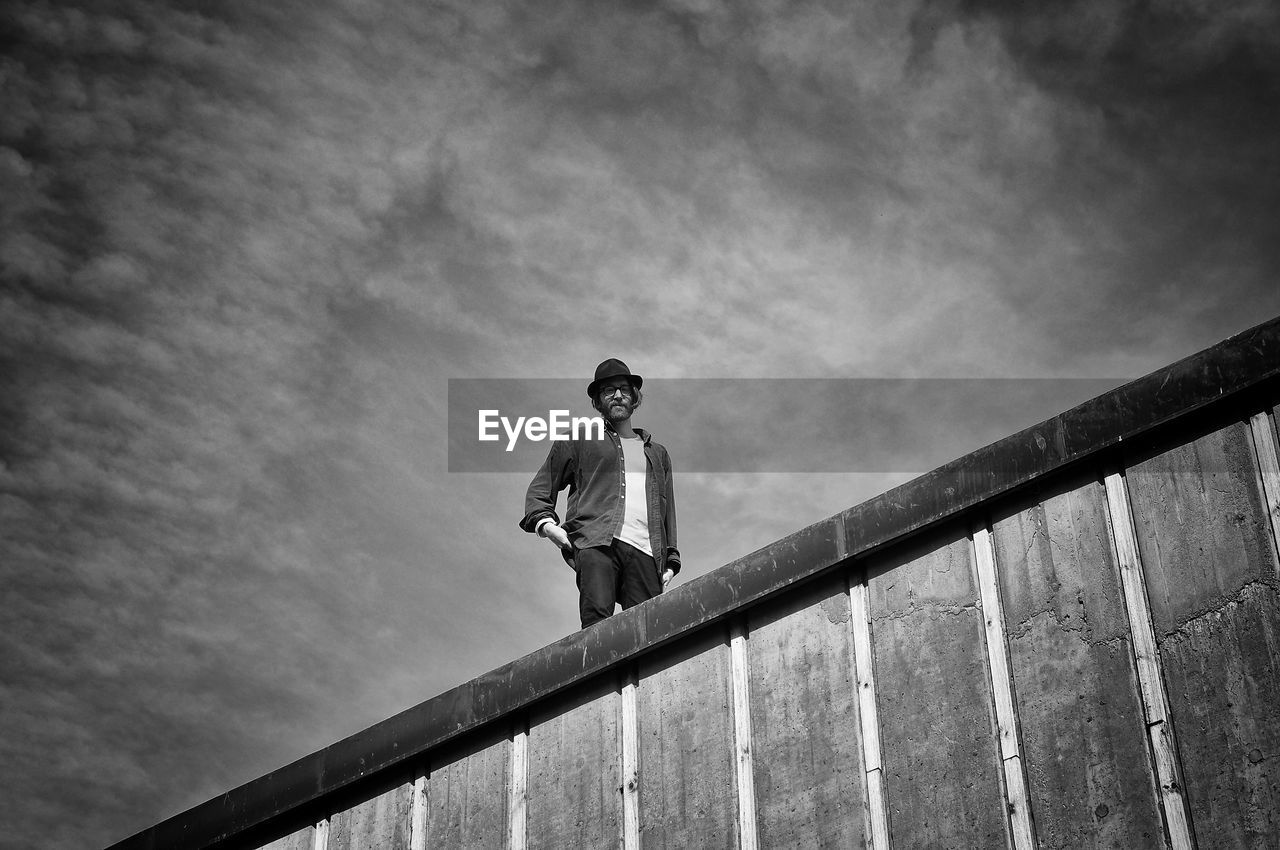 Low angle view of man standing on building against sky