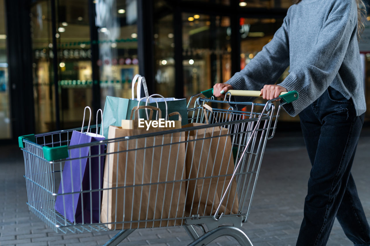 Cropped shot of woman with shopping cart full of purchases