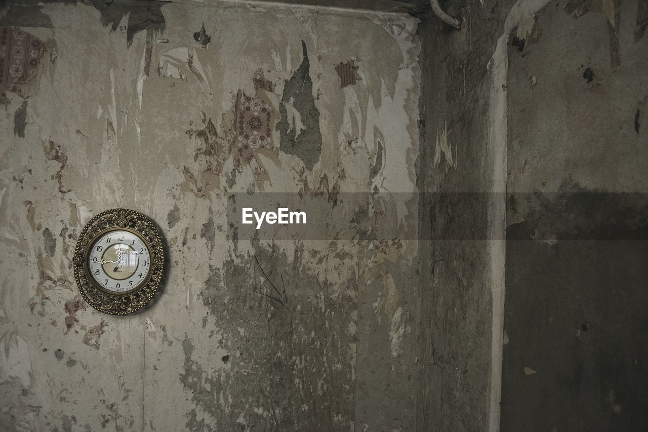 Antique old clock mounted on weathered wall