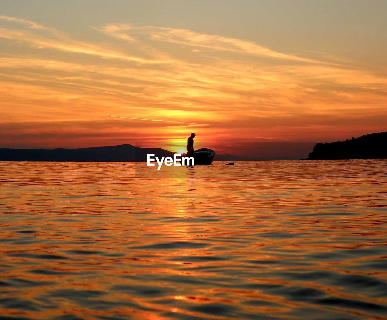 Man sailing in boat at sea against sky during sunset