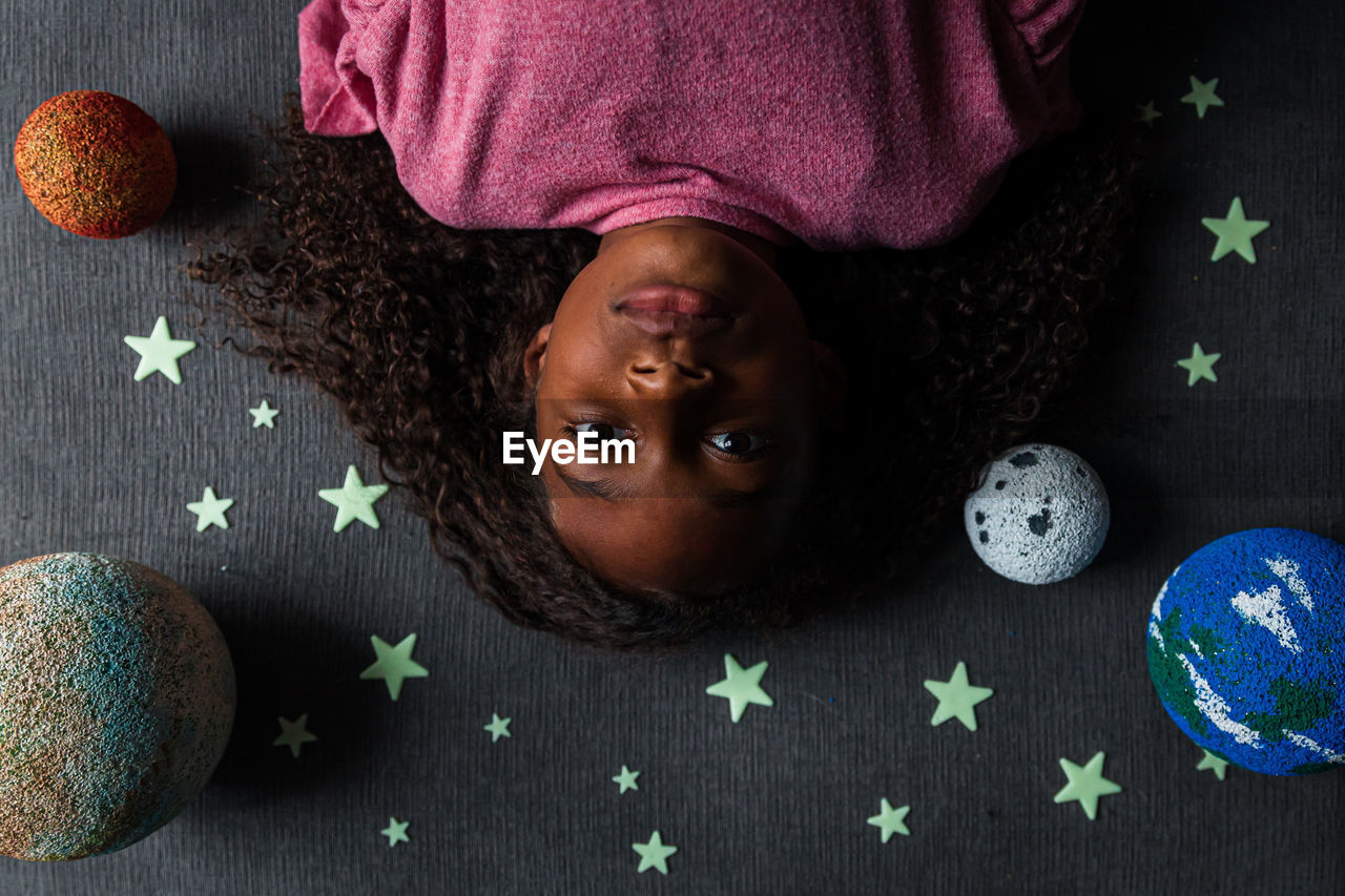 Overhead portrait of girl lying amidst solar system
