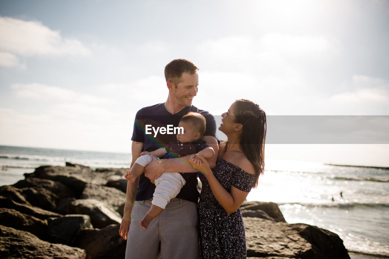 Parents standing on jetty holding infant son