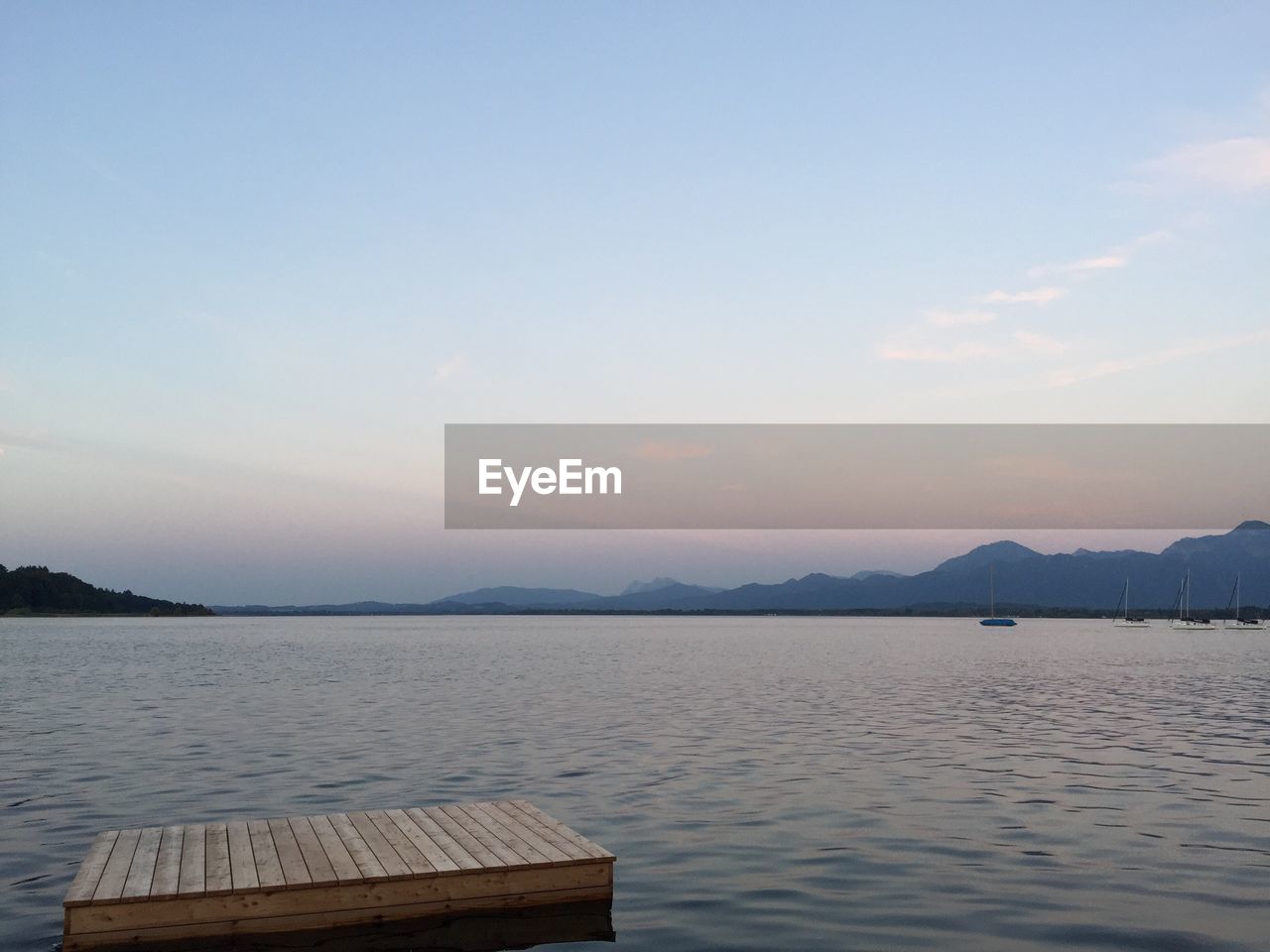 Diving platform in lake against sky at dusk