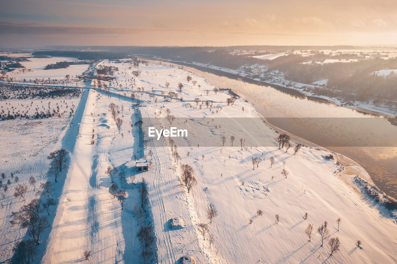 Aerial view of snow covered landscape during sunset