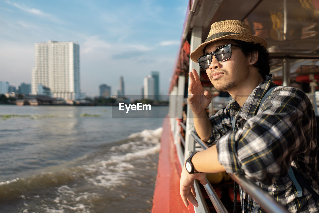 Tourist wearing hat standing in boat on river