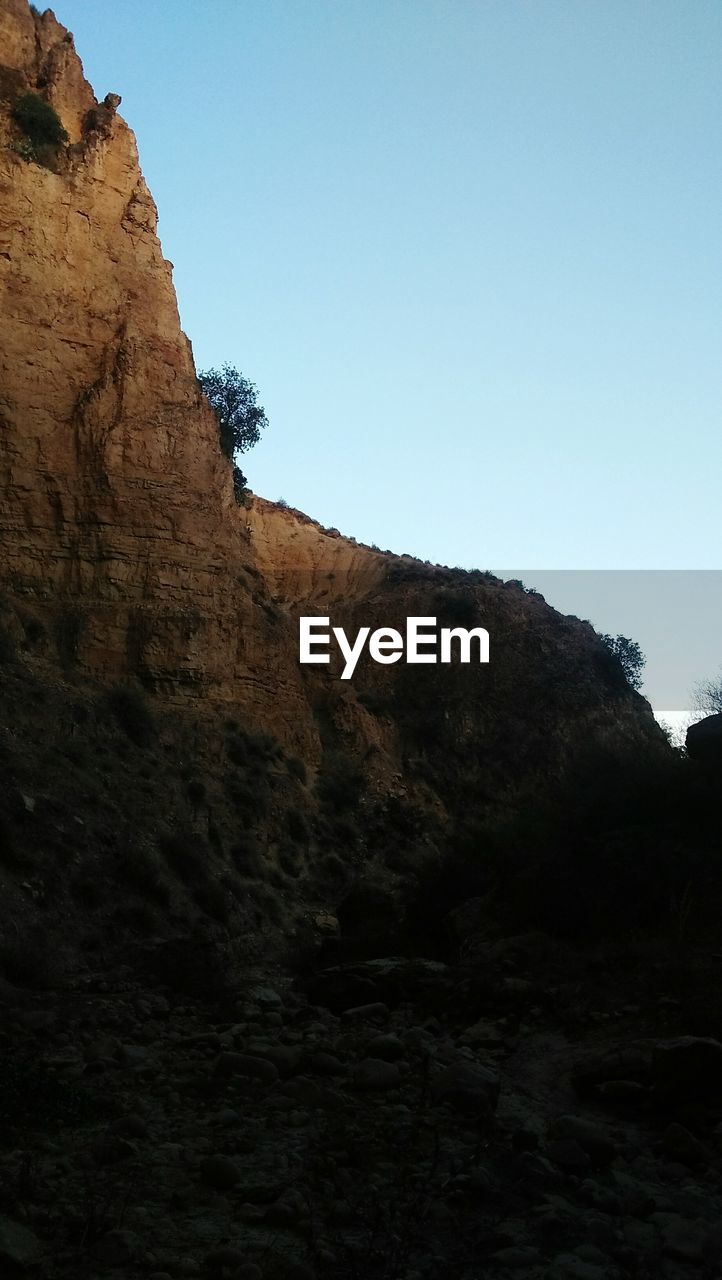 LOW ANGLE VIEW OF ROCK FORMATIONS AGAINST CLEAR SKY