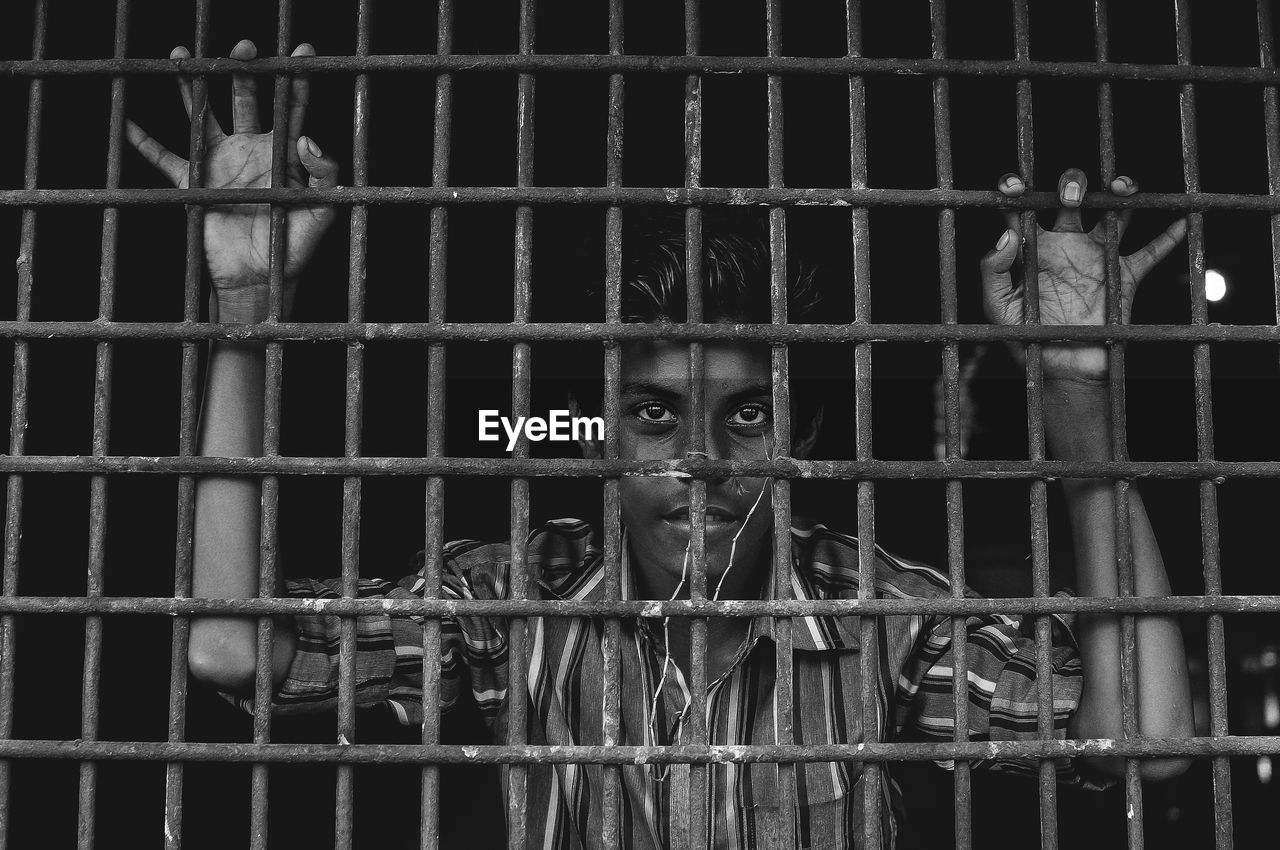 Young man looking through metallic window