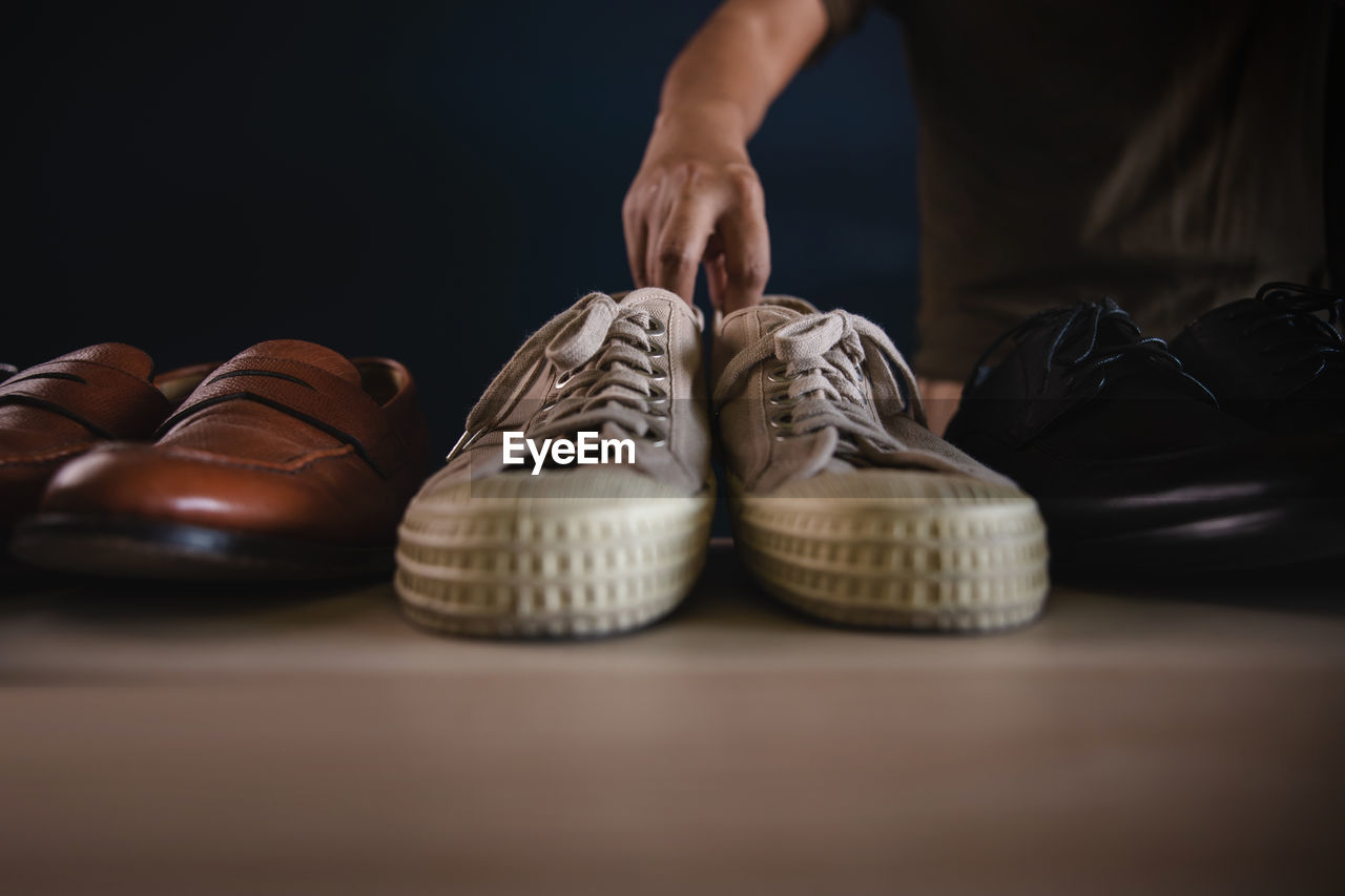 Hands holding white shoes on floor