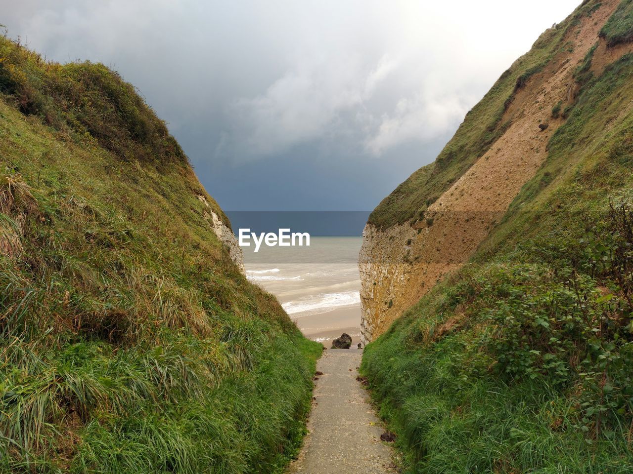 sky, land, water, cloud, coast, nature, cliff, sea, scenics - nature, environment, beauty in nature, beach, plant, landscape, terrain, grass, hill, footpath, travel destinations, no people, travel, tranquility, coastline, overcast, rock, tourism, outdoors, tranquil scene, non-urban scene, green, the way forward, day, holiday, highland, trip, road, vacation