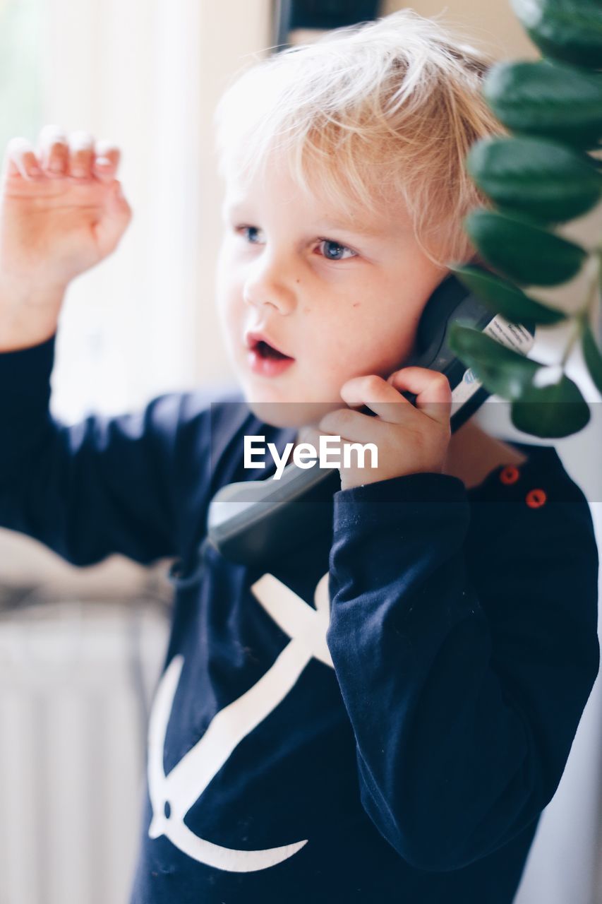 Close-up of cute boy talking on telephone at home