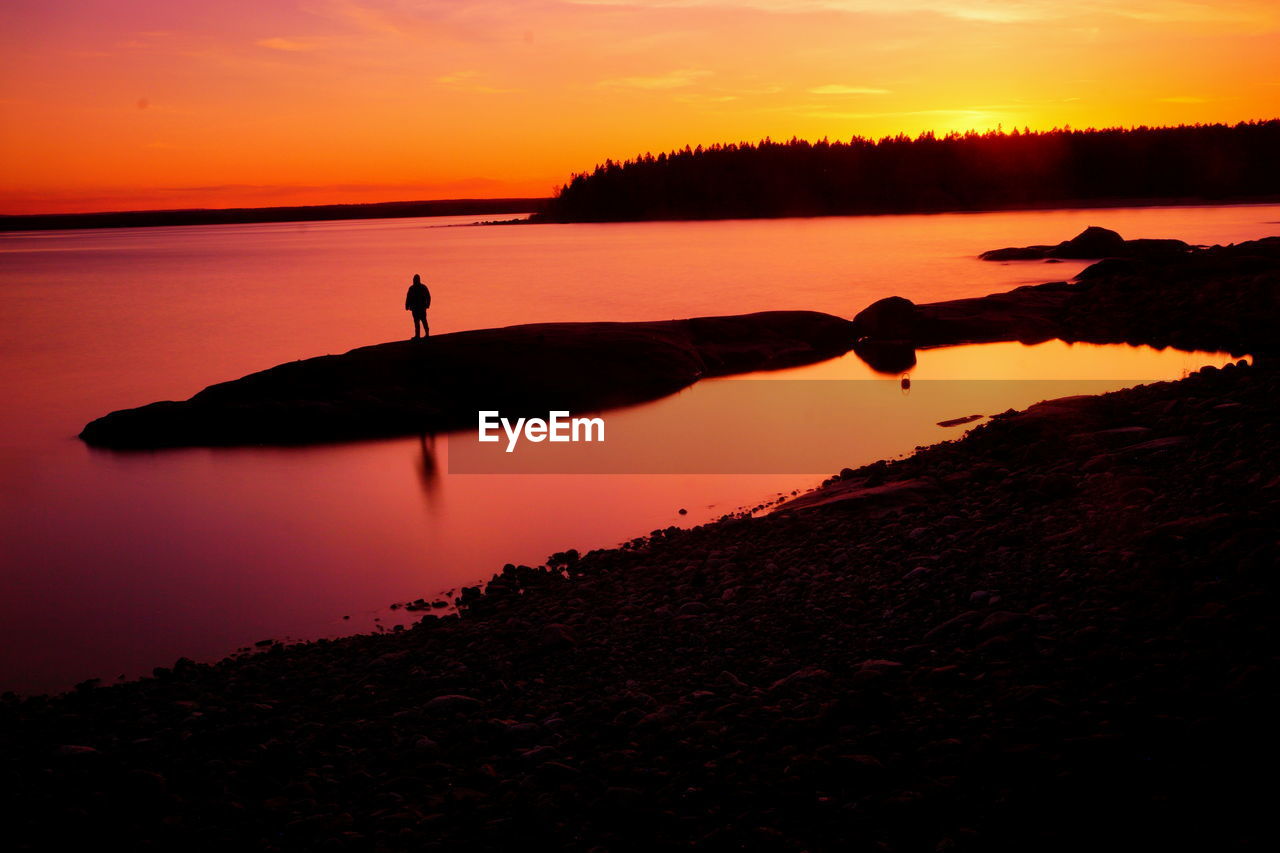 water, sunset, sky, silhouette, dawn, beauty in nature, reflection, scenics - nature, orange color, nature, tranquility, sea, horizon, tranquil scene, land, evening, afterglow, beach, one person, sun, landscape, cloud, idyllic, men, environment, outdoors, non-urban scene, leisure activity, sunlight, activity, travel destinations, animal