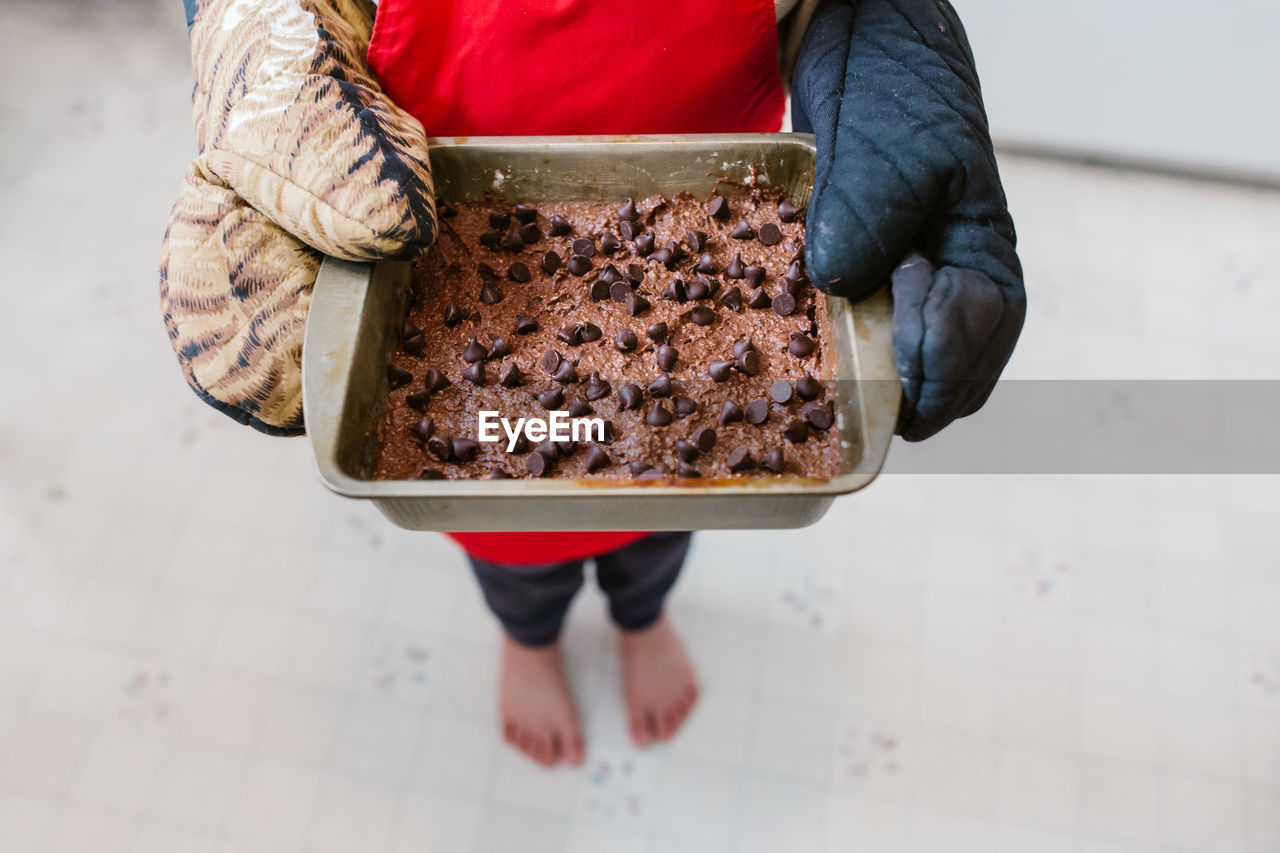 Low section of person holding baked chocolate brownie