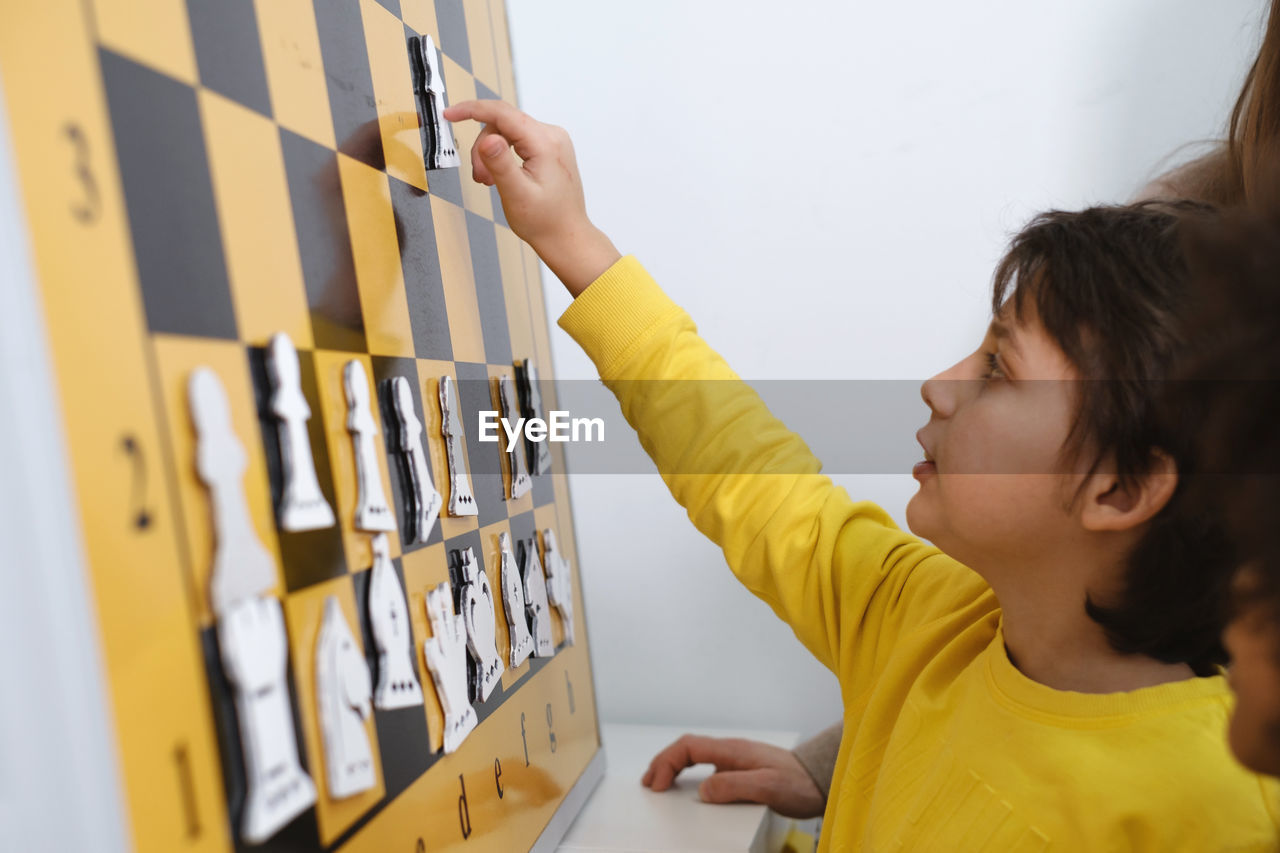 Child thinking hard on chess combinations on the wall on tournament for kids intellectual game