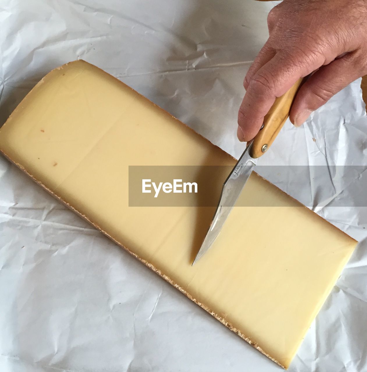 High angle view of hand cutting cheese